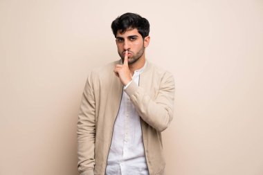 Genç adam bir işaret parmağını ağzına koyarak sessizlik jest gösteren izole duvarın üzerinden