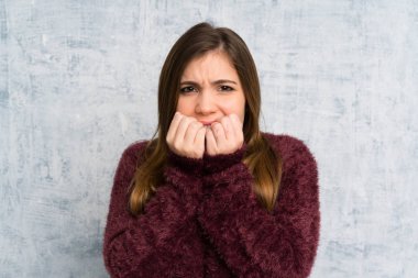 Young girl over grunge wall nervous and scared