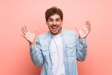 Sürpriz ve şok yüz ifadesi ile pembe duvar sarışın adam