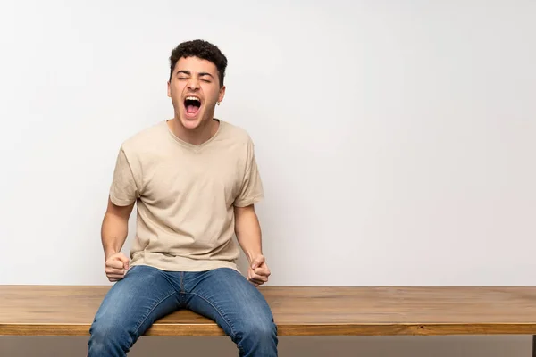 Jovem Sentado Mesa Gritando Para Frente Com Boca Bem Aberta — Fotografia de Stock