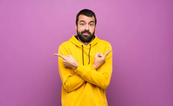 Hombre Guapo Con Sudadera Amarilla Apuntando Los Laterales Que Tienen —  Fotos de Stock