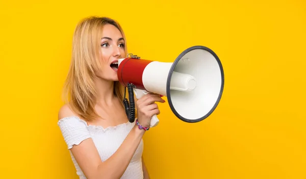 Jonge Blonde Vrouw Geïsoleerde Gele Muur Schreeuwen Door Een Megafoon — Stockfoto