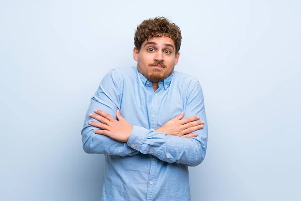 Blonde Man Blue Wall Making Doubts Gesture While Lifting Shoulders — Stock Photo, Image