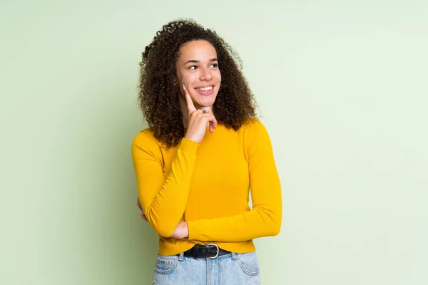 Mujer Dominicana Sobre Fondo Verde Aislado Pensando Una Idea Mientras —  Fotos de Stock