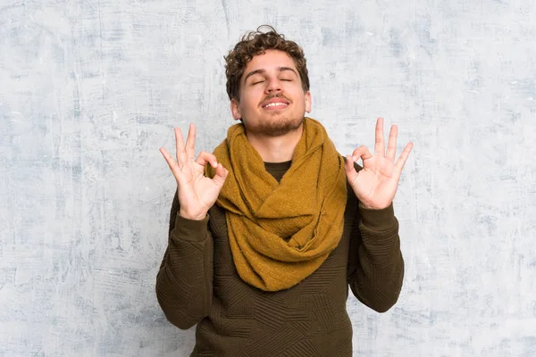 Blonde man over grunge wall in zen pose