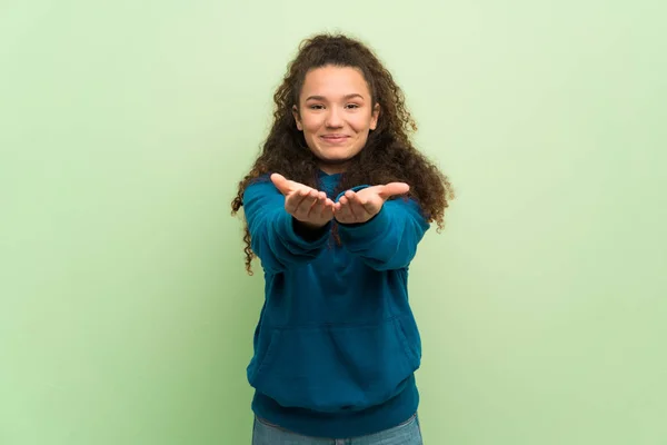 手のひらに架空の Copyspace を保持する緑の壁に広告を挿入するティーンエイ ジャーの女の子 — ストック写真