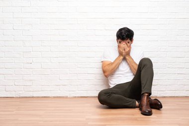 Yorgun ve hasta ifadesiyle yerde oturan genç adam