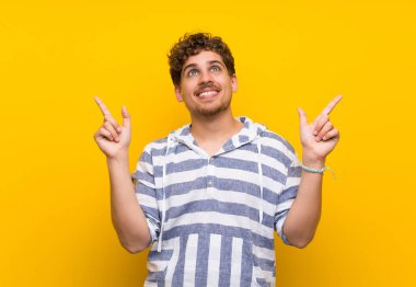 İşaret parmağı ile işaret sarı duvar üzerinde Sarışın adam harika bir fikir