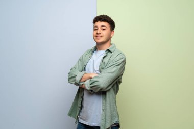 Genç adam silah ile mavi ve yeşil arka plan üzerinde çarpı işareti