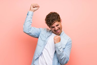 Bir zafer kutluyor pembe duvar üzerinde Sarışın adam