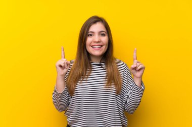 Young girl over yellow wall pointing up a great idea