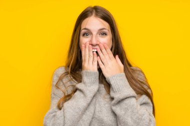 Sürpriz yüz ifadesi ile sarı arka plan üzerinde uzun saçlı genç kadın