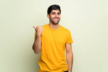 Pembe duvar tarafına işaret eden bir ürün sunmak için genç adam