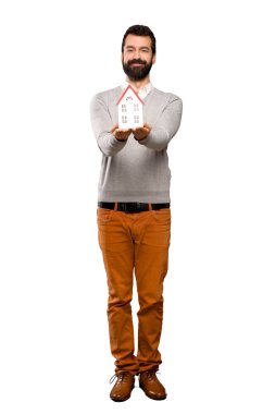 İzole beyaz arka plan üzerinde küçük bir ev tutarak sakallı yakışıklı adam
