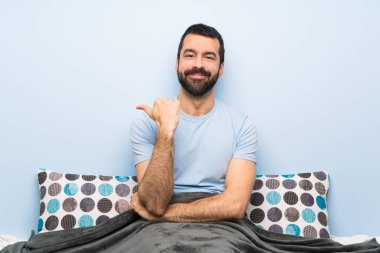 Bir ürün sunmak için yan işaret yatakta Adam