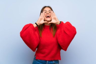 Izole mavi duvar üzerinde genç kadın bağırarak ve bir şey ilan