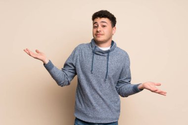 İzole duvar üzerinde genç adam bir şey anlamak için mutsuz