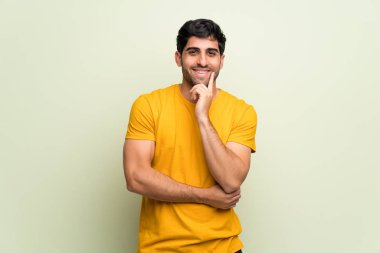 Pembe duvarın üzerinden gülümseyen ve kendinden emin yüzüyle öne bakan genç adam.