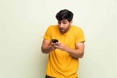 Pembe duvarın üzerindeki genç adam cep telefonuyla şaşırdı.