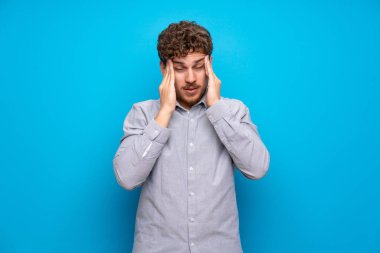 Baş ağrısı ile mavi duvar üzerinde Sarışın adam