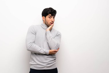 İzole edilmiş beyaz duvardaki genç adam sağa bakarken şaşırdı ve şok oldu.