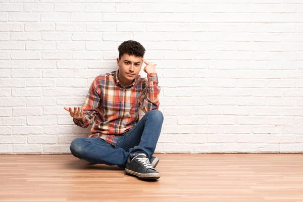 Mladý Muž Sedící Podlaze Který Dělá Gesto Šílenství Dává Prst — Stock fotografie