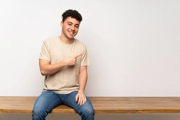 Mladý Muž Sedící Stole Ukazuje Stranu Aby Prezentoval Produkt — Stock fotografie