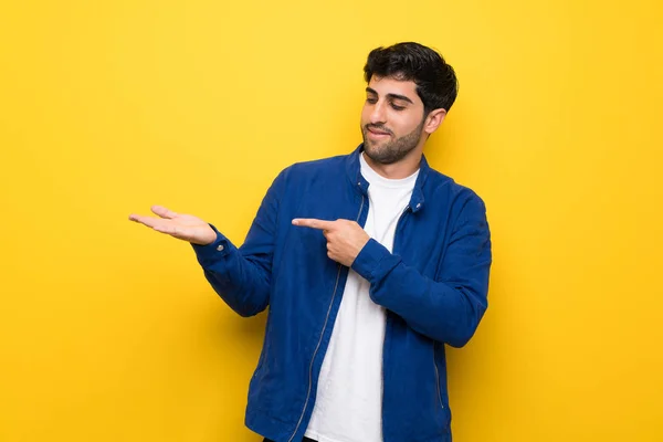 Homem Com Casaco Azul Sobre Parede Amarela Segurando Copyspace Imaginário — Fotografia de Stock