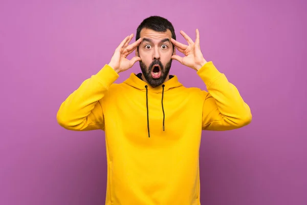 Handsome man with yellow sweatshirt with surprise expression