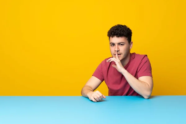 Renkli Duvarı Masası Olan Genç Bir Adam Sessizlik Işareti Gösteriyor — Stok fotoğraf