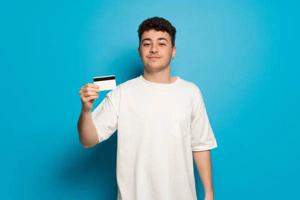 Mladý Muž Nad Modrým Pozadím Drží Kreditní Kartu — Stock fotografie