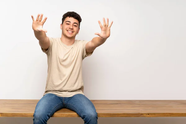 Mladý Muž Sedí Stole Počítá Deset Prstů — Stock fotografie