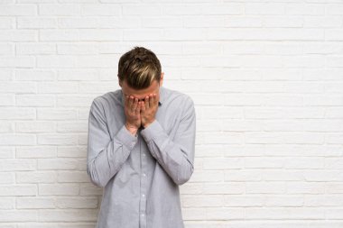 Yorgun ve hasta ifade ile beyaz tuğla duvar üzerinde Blonde adam