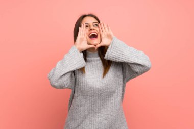Pembe duvarın arkasında genç bir kadın bağırıyor ve bir şeyler söylüyor.