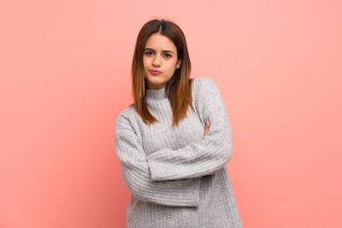 Pembe duvarın arkasındaki genç kadın üzgün.