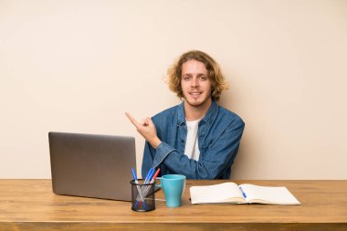 Yan parmak işaret eden bir laptop ile sarışın adam