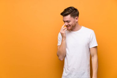 Kahverengi duvarın üzerinde kızıl saçlı adam çok gülümsüyor