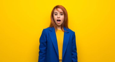 Yüzünde sürpriz bir ifade olan, trençkotlu genç kızıl saçlı kadın.