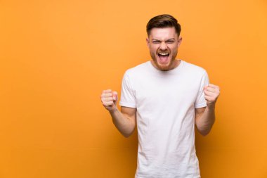 Kahverengi duvar üzerinde Redhead adam kazanan pozisyonda bir zafer kutluyor