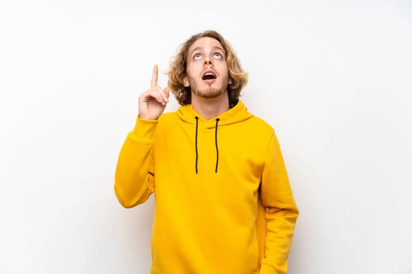 Blond Man Med Sweatshirt Över Vit Vägg Pekar Upp Och — Stockfoto