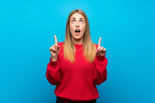 Woman Red Sweater Blue Wall Surprised Pointing — Stock Photo, Image