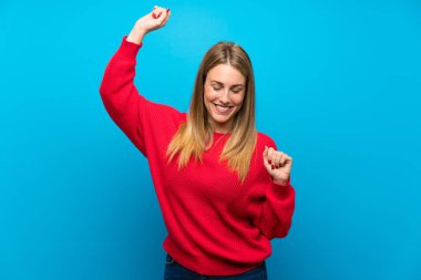 Bir zaferini kutluyor mavi duvarın üzerinden kırmızı kazaklı kadın