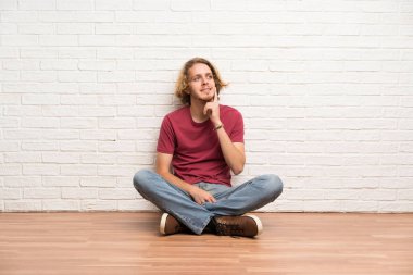 Sarışın adam yukarı bakarken bir fikir düşünerek katta oturan