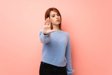 Pembe arka planda genç kızıl saçlı kadın yanlış düşünen bir durumu inkar etmekten vazgeçiyor.