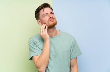 Renkli arka plan ayakta ve bir fikir düşünme üzerinde Redhead adam