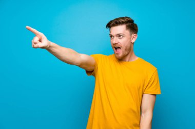 Mavi duvarın üzerinde redhead adam uzağa işaret