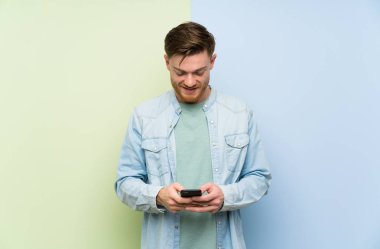 Renkli arka plan üzerinde Redhead adam cep ile bir mesaj gönderme