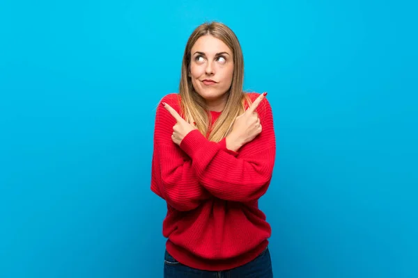 疑問を持つ根を指している青い壁に赤いセーターの女性 — ストック写真