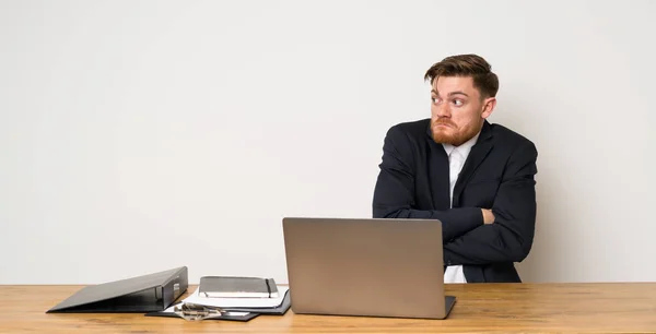 Businessman in a office making doubts gesture while lifting the shoulders