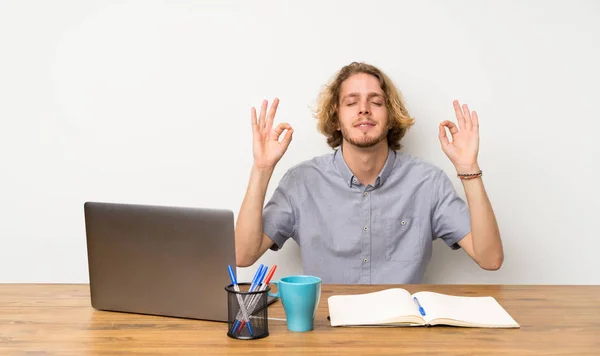 Blonde man with a laptop in zen pose